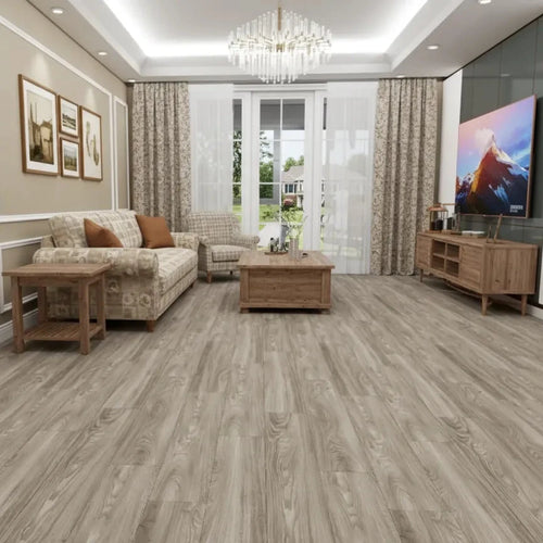 A modern living room with light gray wood-look vinyl or laminate flooring, featuring a beige sofa, wooden coffee table, and a large TV on a console against a dark accent wall.